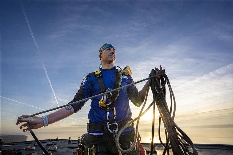 Technician rigging ropes on a commercial roof at sunrise